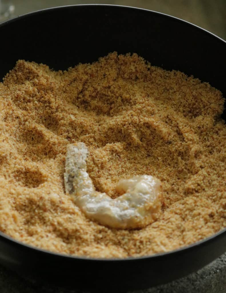 adding the shrimp coated in egg wash and the added to the bowl of bread crumbs.