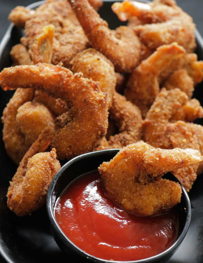 breaded shrimp deep fried and served on a plate served with sauce.