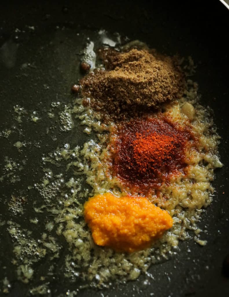 adding the spice powders to the cooking ginger to make the shrimp korma.