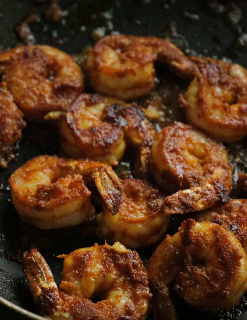 charred tandoori shrimp in a pan.