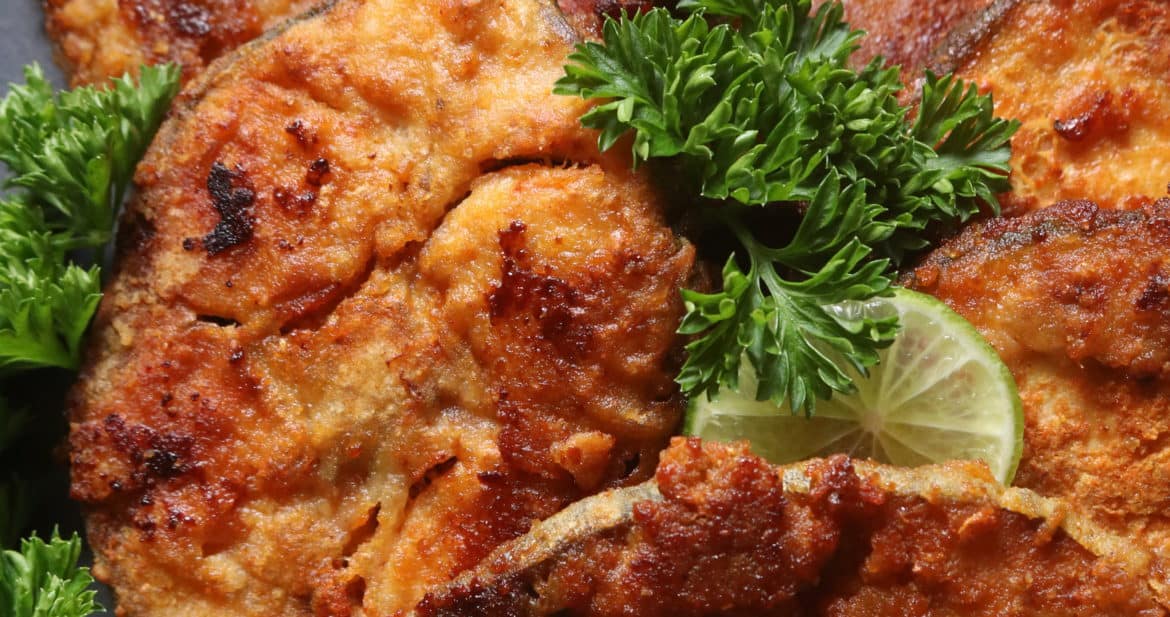 fish fry steaks placed on platter with lime and parsley garnishing.