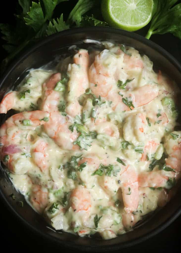 creamy shrimp salad with lime wedges and garnish.