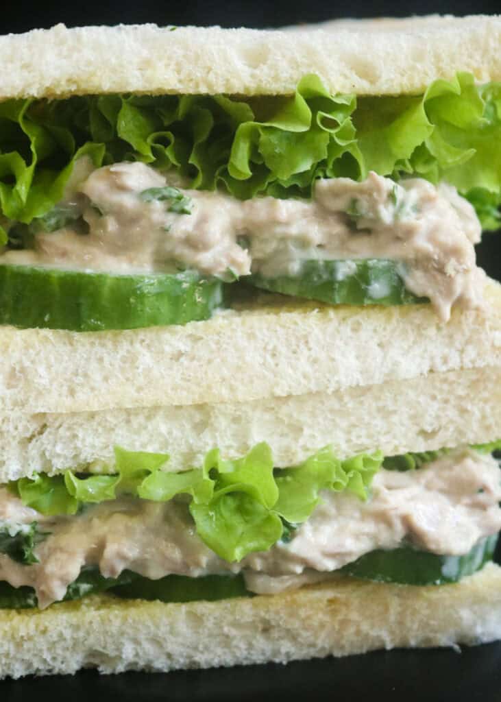 classic tuna salad sandwich with cucumbers and stacked together.