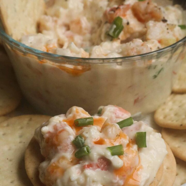 shrimp dip on a cracker with a bowl of dip.